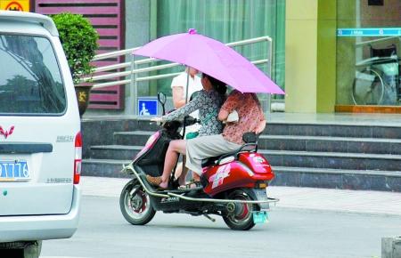 撑伞电动车随处可见 遮了阳光多了危险